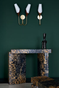 Roberto Sironi marble console with a black vase on top & Joe Armitage appliques on a green backdrop