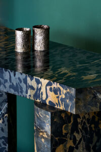 Roberto Sironi marble console with two brass cups on a green backdrop