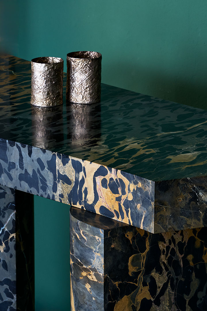 Roberto Sironi marble console with two brass cups on a green backdrop